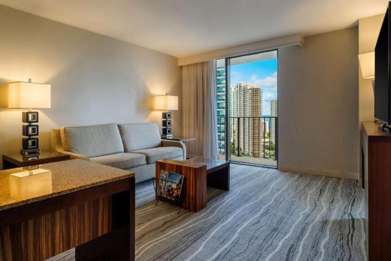 Sala de estar de suite con sofá, mesa de centro y balcón con vistas a los rascacielos en Hyatt Regency Miami