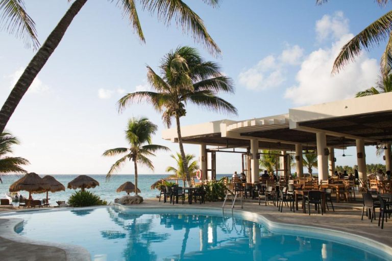 Piscina exterior con restaurante frente al mar y palmeras tropicales en Paamul Hotel
