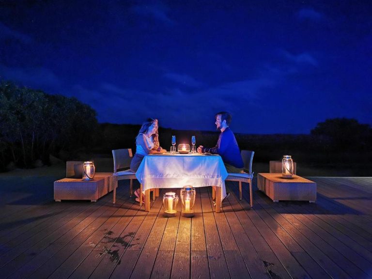 Cena romántica a la luz de las velas en terraza exterior del Finch Bay Galapagos Hotel bajo el cielo nocturno
