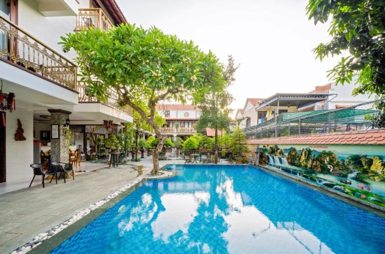 Piscina exterior rodeada de jardín con árboles y bonsáis en Bonsai Villa Hoi An, Vietnam