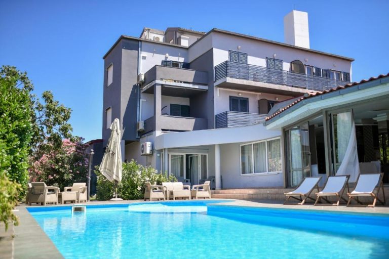Piscina exterior con tumbonas y terraza del Levant Residence rodeado de jardines