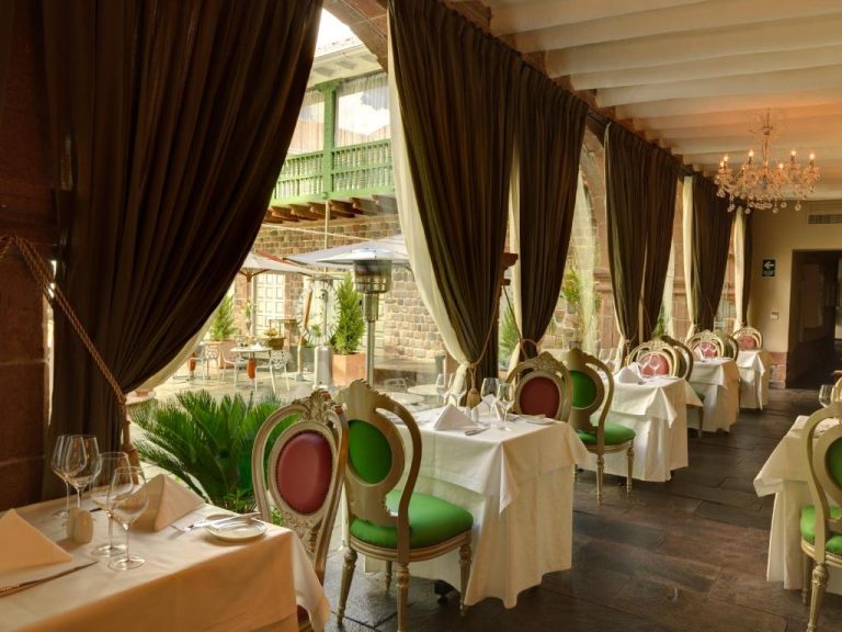 Restaurante elegante con sillas verdes y rosas del Aranwa Cusco Boutique Hotel con decoración colonial