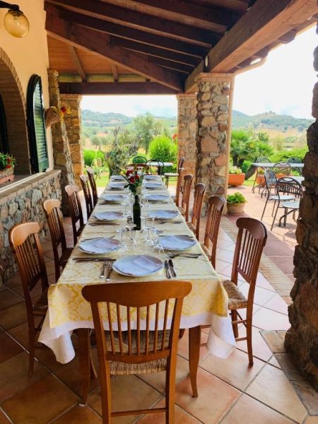 Terraza comedor exterior con mesa larga preparada para grupos en el Hotel Janas con vistas al campo