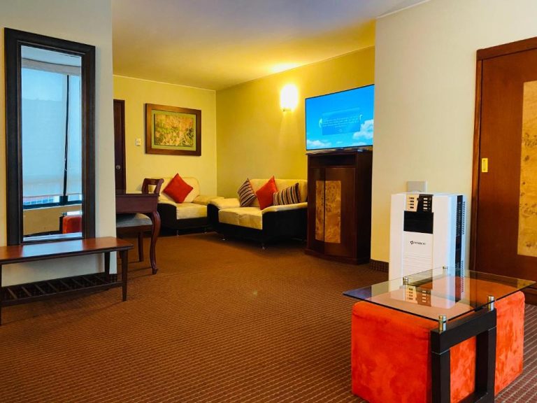 Salón de suite con sofás, televisor de pantalla plana y mesa de cristal en Hotel Continental Lima