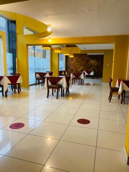 Restaurante interior del Hotel Continental Lima con mesas vestidas y paredes amarillas