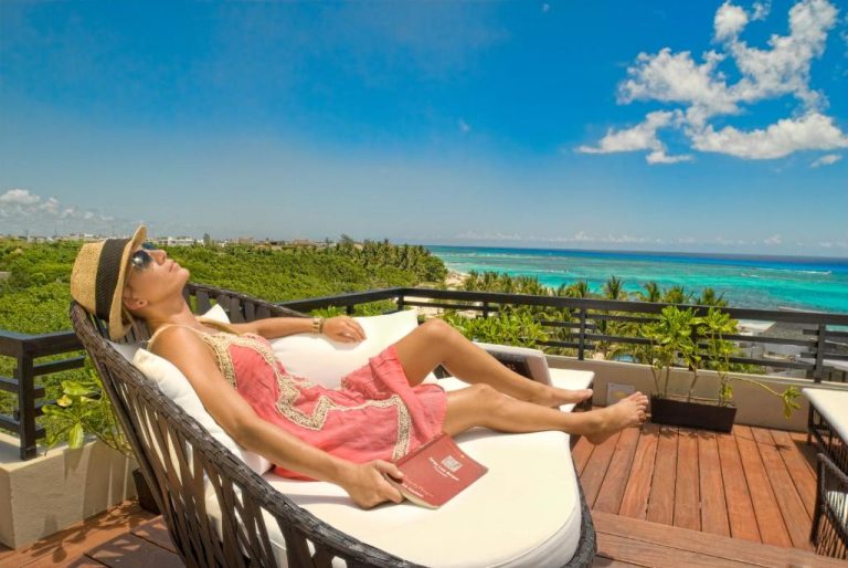 Mujer relajándose en terraza privada con vista al mar turquesa en La Divina by Aldea Thai