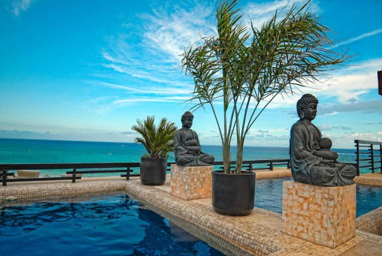 Piscina infinita con estatuas de Buda y vista al mar turquesa en La Divina by Aldea Thai
