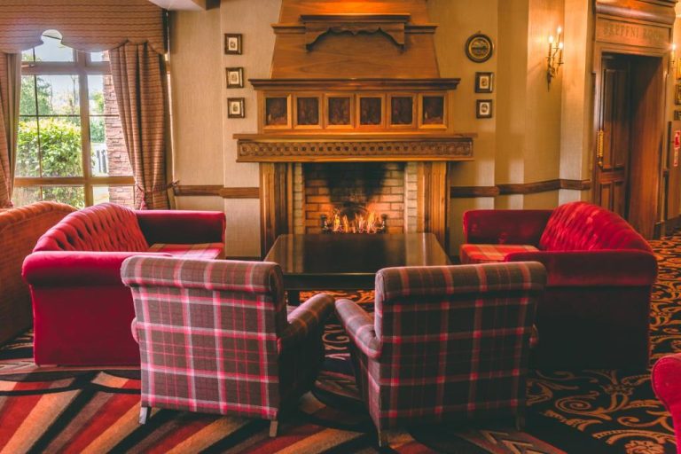 Salón acogedor con chimenea encendida y sillones de cuadros del Hotel Kilmore