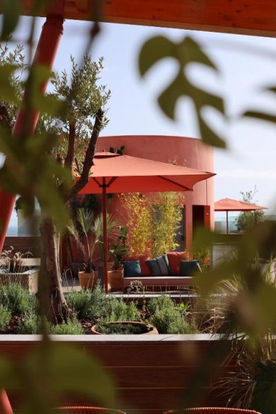 Terraza jardín con sombrillas rojas y zona lounge exterior del Three House Hotel