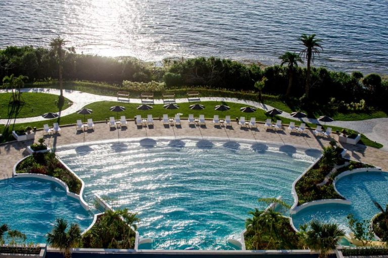 Piscina exterior con tumbonas y vistas al mar del Hotel Monterey Okinawa Spa & Resort en Japón