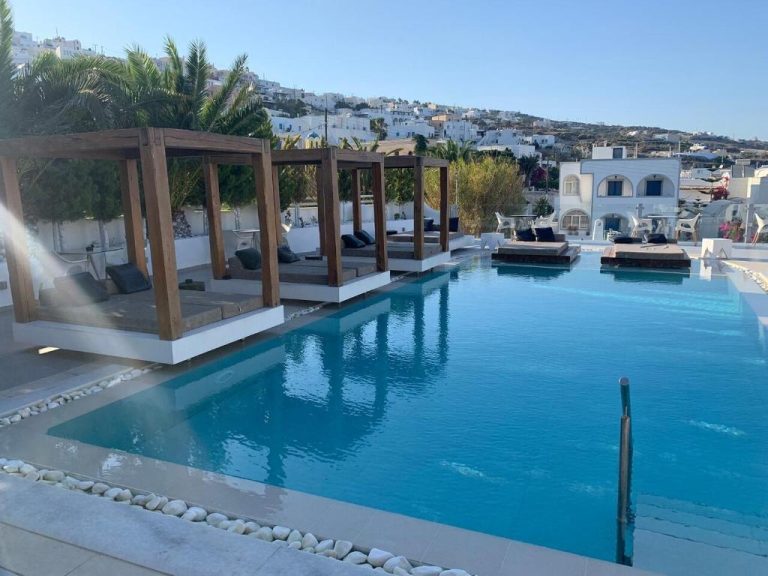 Piscina infinity con cabanas de madera y vistas al pueblo blanco en Callia Retreat Suites Adults Only Santorini