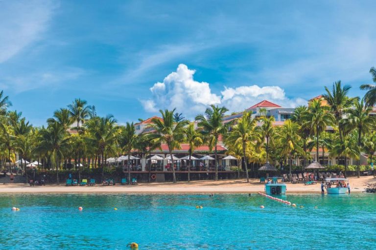 Vista desde el mar de la playa y resort del Mauricia Beachcomber Resort & Spa con palmeras