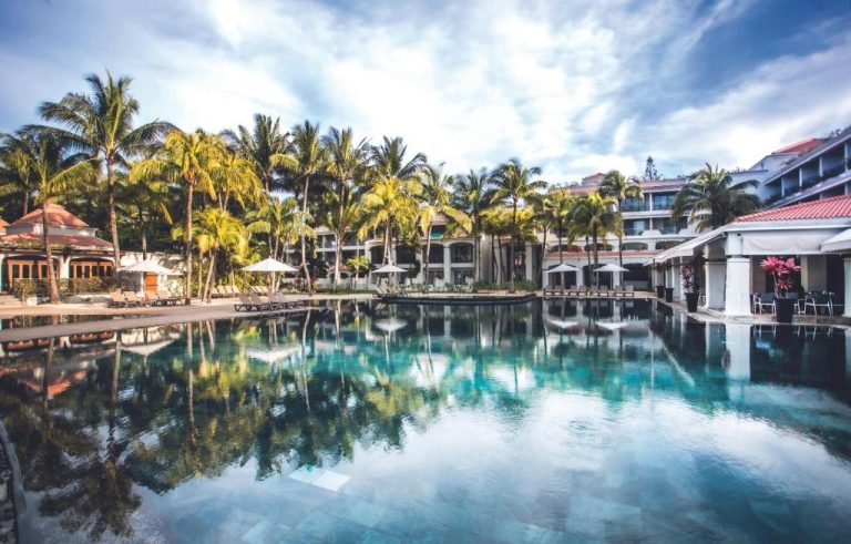 Piscina principal con palmeras tropicales del Mauricia Beachcomber Resort & Spa en Mauricio