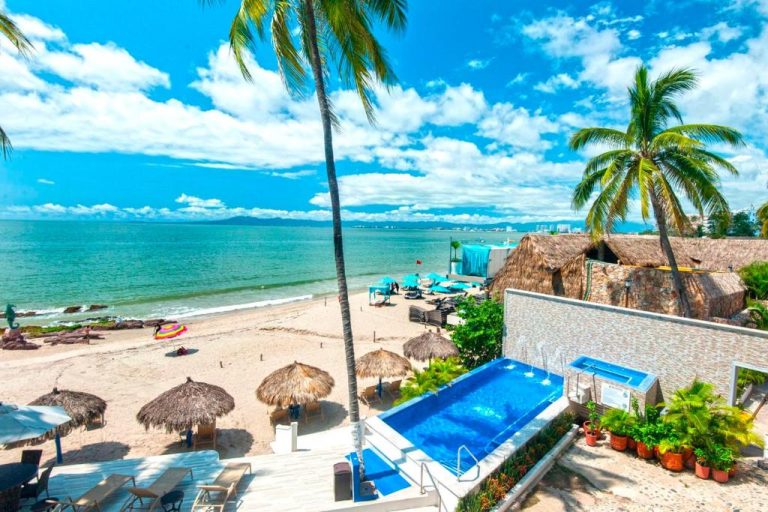 Piscina exterior y playa con palmas del Vallarta Shores Beach Hotel en Puerto Vallarta