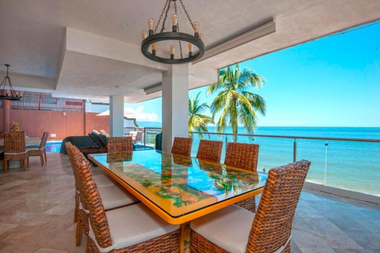 Terraza comedor con mesa de cristal y sillas de ratán con vista al mar en Vallarta Shores Beach Hotel