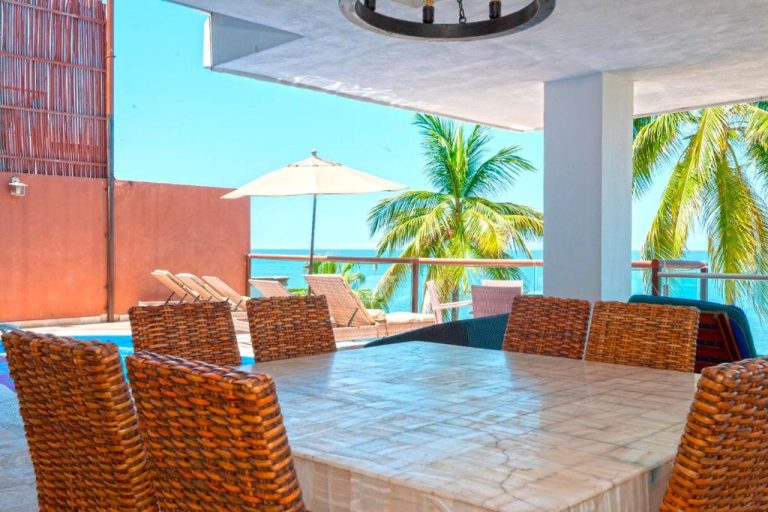 Terraza comedor con sillas de mimbre y vista al mar y palmeras en Vallarta Shores Beach Hotel