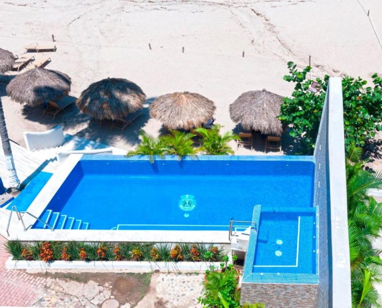 Vista aérea de la piscina exterior del Vallarta Shores Beach Hotel con palapas y playa de arena