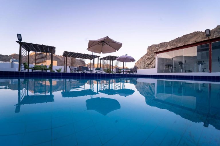 Piscina exterior del Riyam Hotel con tumbonas, sombrillas y vistas a las montañas del desierto