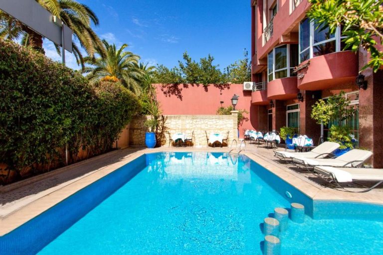 Piscina exterior con tumbonas y terraza del Hotel Akabar rodeada de palmeras y jardín