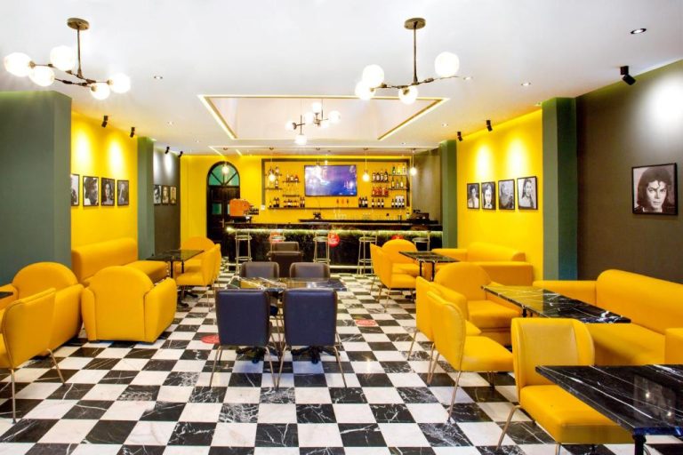 Bar y salón con decoración amarilla y suelo de ajedrez en el Hotel Akabar