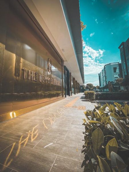 Fachada exterior dorada del hotel The Upper House Batu Kawan con acceso peatonal y jardines