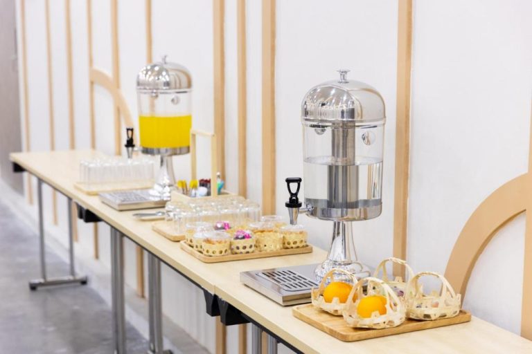 Estación de bebidas y desayuno buffet con dispensadores de agua y zumo en el Nappiness Hotel