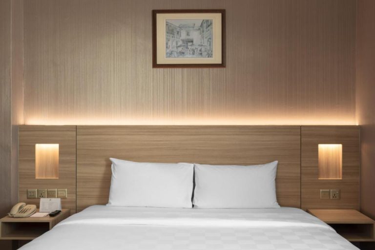 Habitación doble con cama matrimonial y cabecero de madera iluminado en Cititel Penang