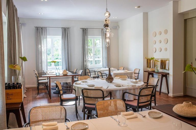 Elegante restaurante interior del Boutique Hotel Boškinac con mesas redondas y sillas de mimbre