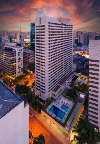 Vista aérea del Radisson São Paulo Paulista con piscina exterior y skyline de la ciudad al atardecer