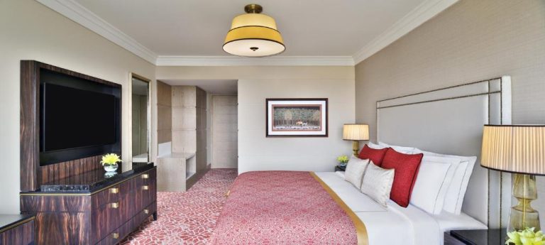 Lujosa habitación deluxe con cama king size y decoración en rojo del Taj Mahal New Delhi