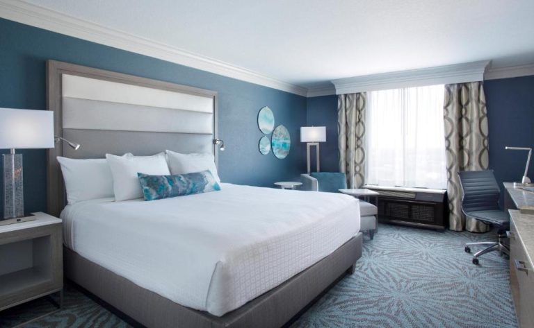 Habitación king size con decoración azul y escritorio de trabajo en Rosen Centre Hotel Orlando