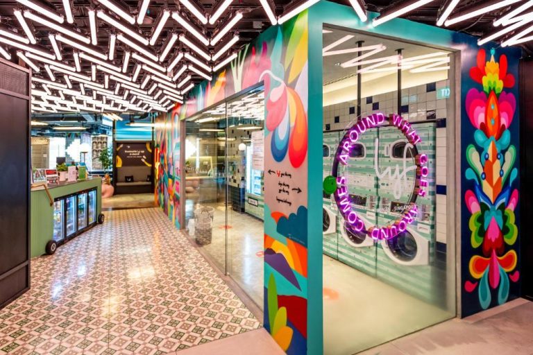 Lavandería compartida con murales de arte urbano coloridos en el hotel lyf Funan Singapore