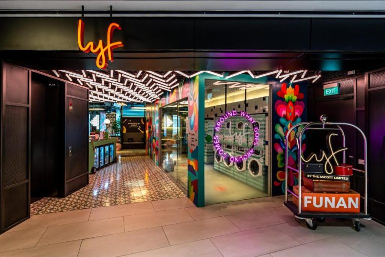 Entrada colorida y vibrante del lobby del hotel lyf Funan Singapore con murales artísticos y neones