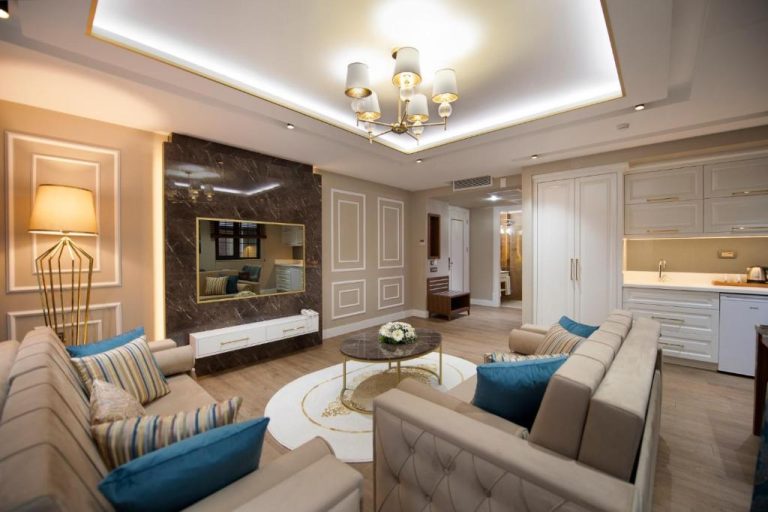 Amplio salón de suite de lujo con sofás beige y cojines azules en Elysium Green Suites