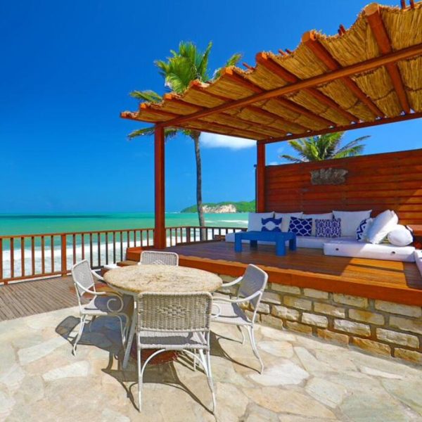 Terraza con pergola y vistas al mar turquesa del Manary Praia Hotel con zona lounge y palmeras