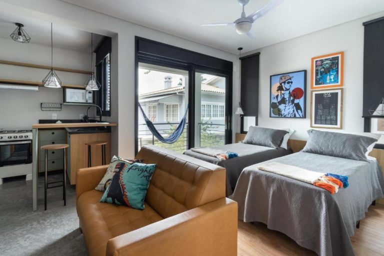 Estudio moderno con dos camas, sofá de cuero y cocina integrada en Hospedaria da Lagoa