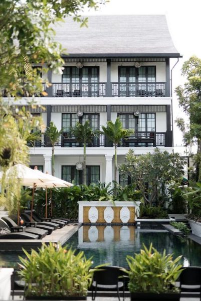 Piscina exterior con jardín tropical y tumbonas del Hotel Aksara Heritage en Chiang Mai