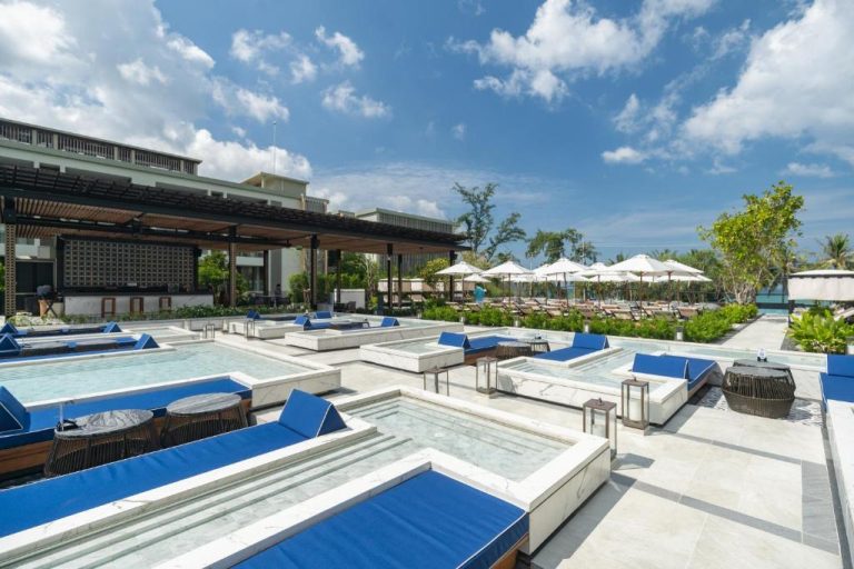 Piscina exterior con tumbonas azules y bar del Four Points by Sheraton Phuket Patong Beach Resort