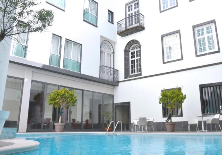Piscina exterior en el patio interior del Hotel Do Colegio con terraza y edificio histórico blanco