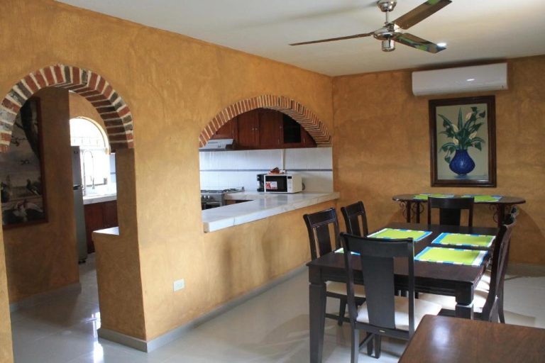 Comedor con mesa de madera y cocina integrada con arcos de ladrillo en Hotel La Casona Real