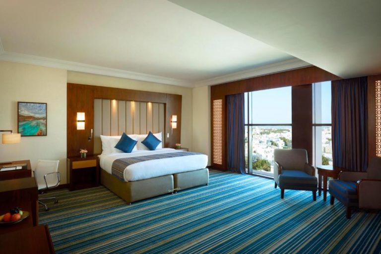 Habitación deluxe con cama king size y vistas panorámicas a la ciudad en Royal Tulip Muscat