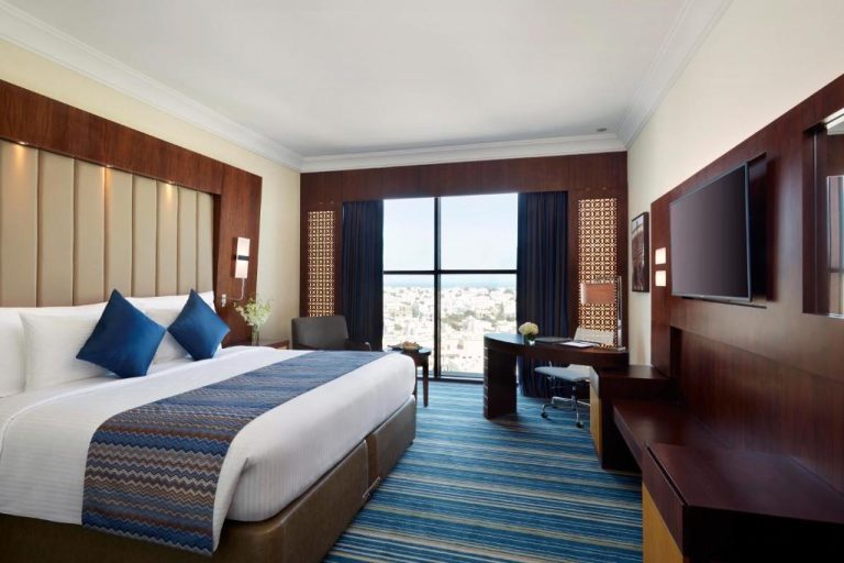 Habitación deluxe con cama king size y vistas panorámicas a la ciudad en Royal Tulip Muscat