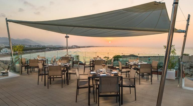 Terraza restaurante al atardecer con vistas al mar en Crowne Plaza Muscat by IHG