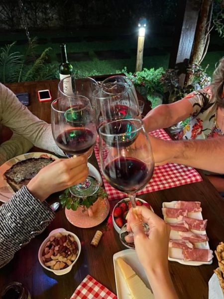 Brindis con vinos tintos en la terraza nocturna de Pousada Vila Rosada con tabla de embutidos y quesos