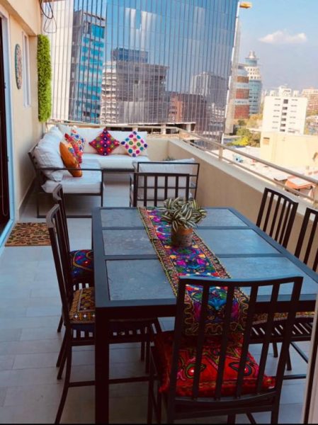 Terraza con comedor exterior y zona lounge del apartamento Encomenderos 200 El Golf con vista al skyline de Santiago