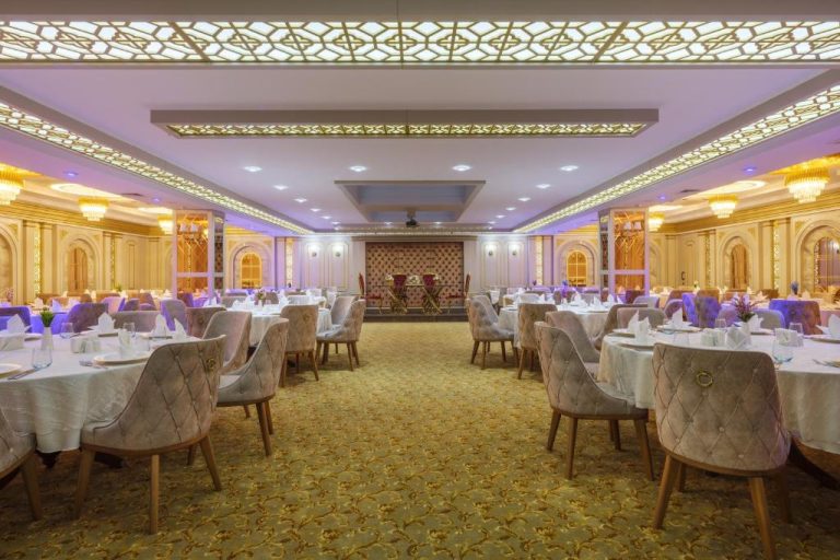 Salón de banquetes de lujo con mesas elegantes y decoración dorada en Elysium Green Suites