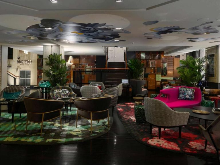 Lujoso lobby bar del QT Sydney con sofás coloridos, alfombras artísticas y decoración ecléctica de diseño