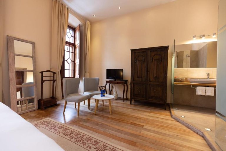 Habitación con suelo de madera, armario antiguo y baño integrado en Casa El Edén