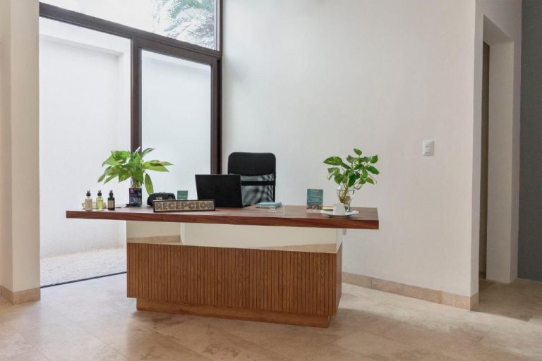 Recepción moderna con escritorio de madera y plantas en Lahun Suites Playa del Carmen