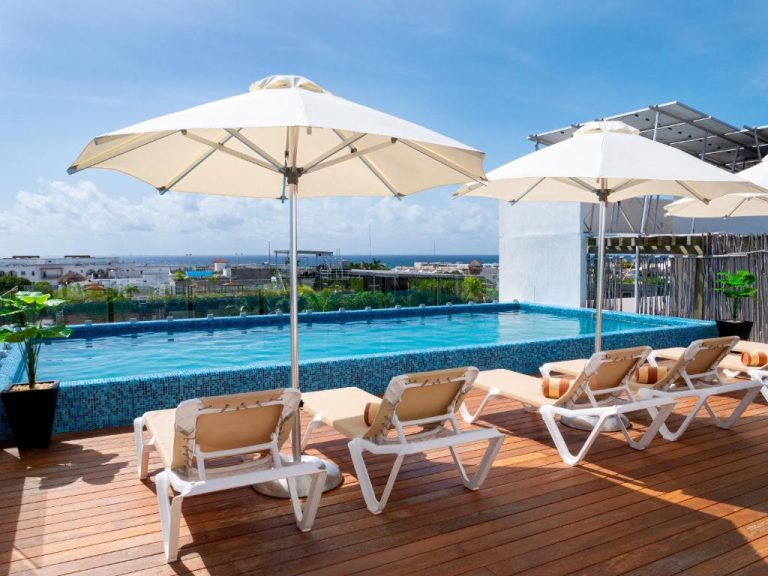 Piscina rooftop con tumbonas y vistas al mar en Lahun Suites Playa del Carmen